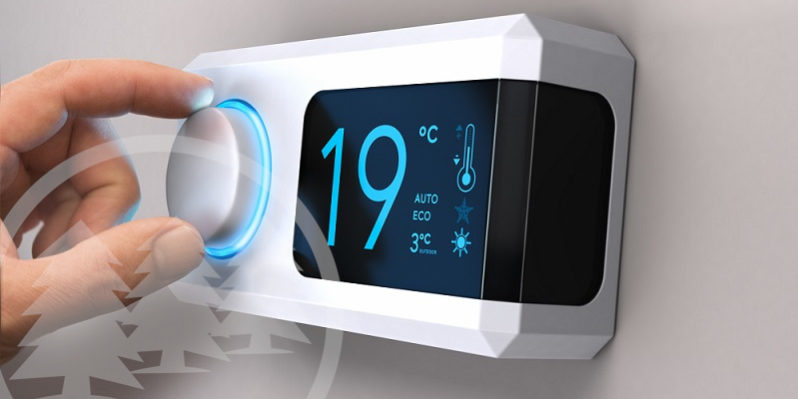 Hand turning a home thermostat knob to set temperature on energy saving mode | energy-saving tips for HOA