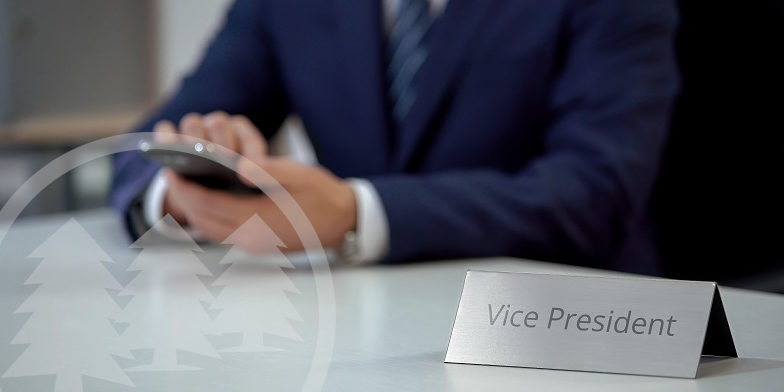man in suit sitting with hands on desk with vice president tag | role of the HOA vice president