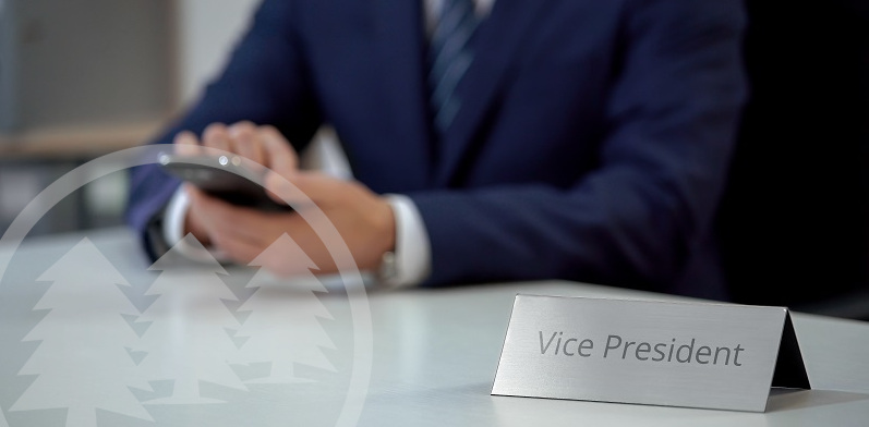 man in suit sitting with hands on desk with vice president tag | role of the HOA vice president