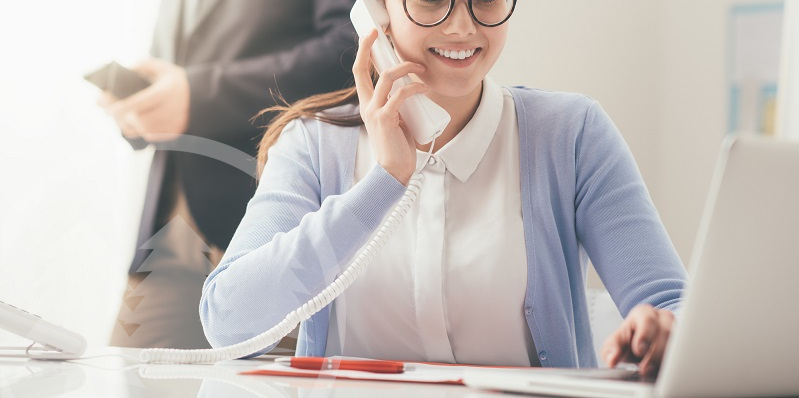 smiling woman working in office while talking on phone | roles of an HOA secretary