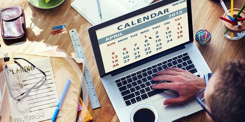 man looking at calendar on laptop with eyeglasses and documents on the table | how to plan an HOA community event