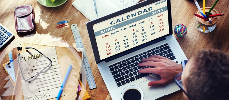 man looking at calendar on laptop with eyeglasses and documents on the table man looking at calendar on laptop with eyeglasses and documents on the table | how to plan an HOA community event
