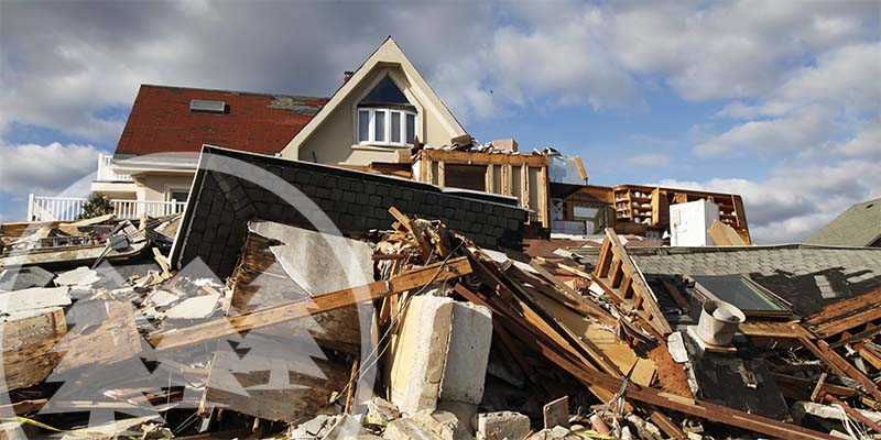 pieces of woo scattered in front of a broken house | hoa natural disaster preparedness